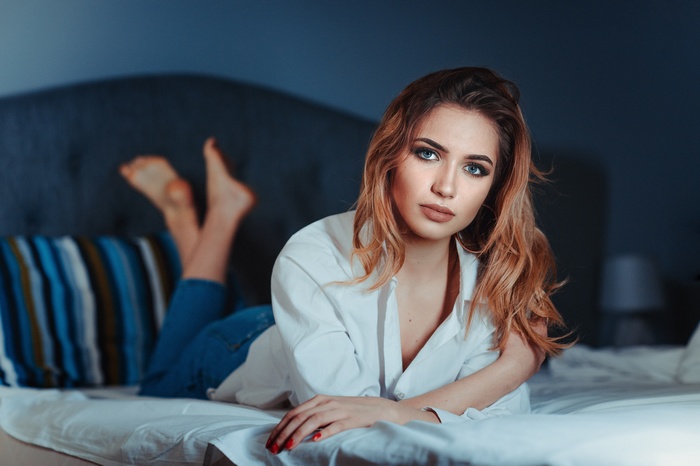 Woman with blue eyes and red hair in bed