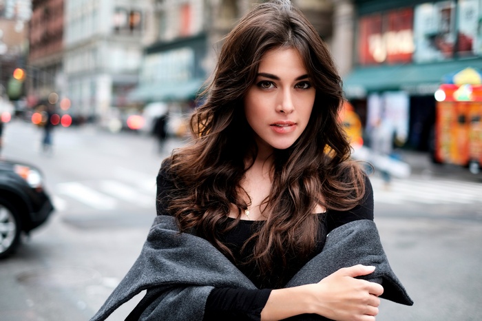 Woman with brown hair and grey coat in city