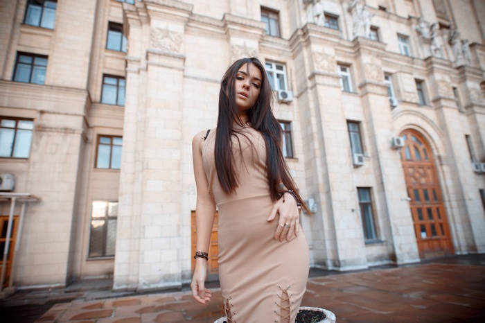 Woman in a beige dress standing in front of a building