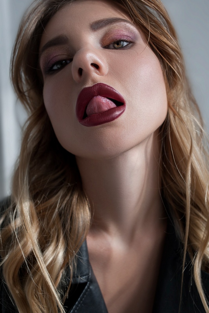 Woman with dark lipstick sticking out tongue