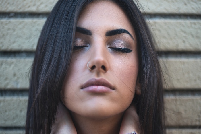 Woman with nose ring and eyeliner, closed eyes