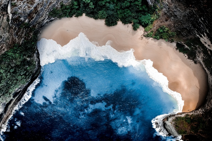 Aerial view of a tropical beach with cliffs and ocean waves