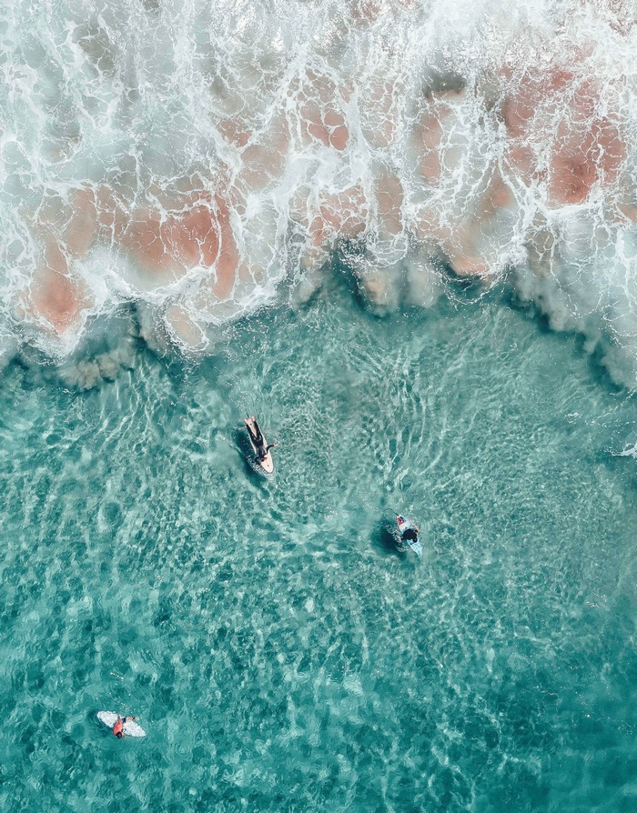 Surfers in turquoise water with breaking waves