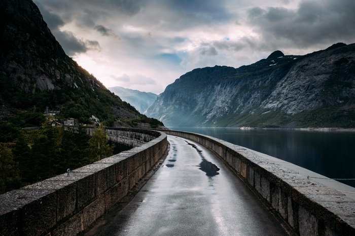 Road on a dam with mountains and a lake