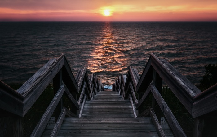 Wooden stairs leading to the ocean at sunset