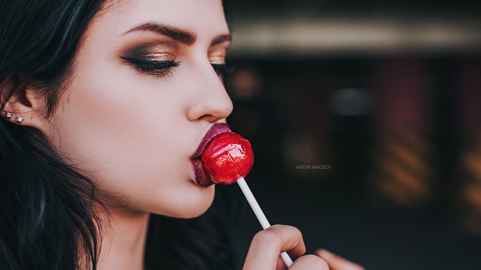 Woman with makeup eating a lollipop