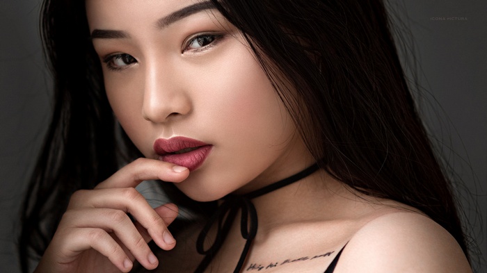 Asian woman with finger on lips and tattoo