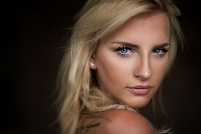 Portrait of a blonde woman with blue eyes and a tattoo