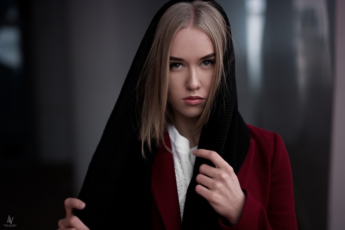 Woman with blonde hair wearing a black scarf and red coat