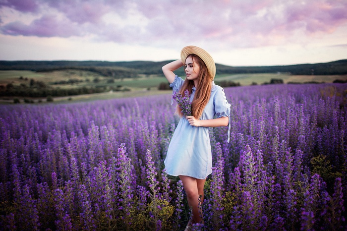 Woman in a blue dress and hat in a lavender field