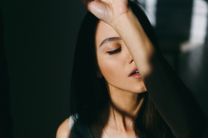 Woman with arm over face in shadow and light