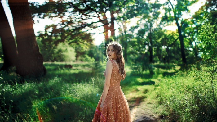 Woman in a dress in a forest with solar flare