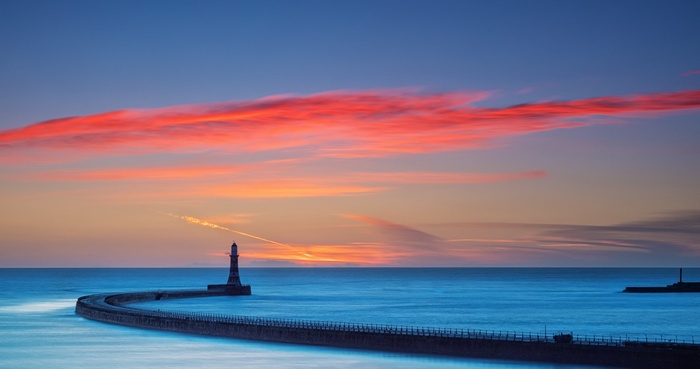 Lighthouse on a pier at sunset with colorful clouds