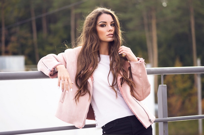 Woman with long brown hair wearing a pink jacket