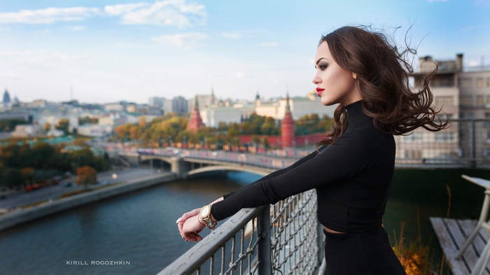 Woman in black clothing on balcony overlooking Moscow cityscape