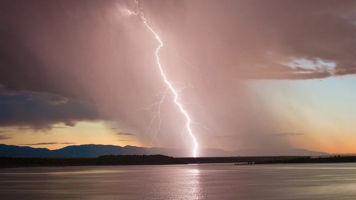 Lightning strike over a lake at sunset