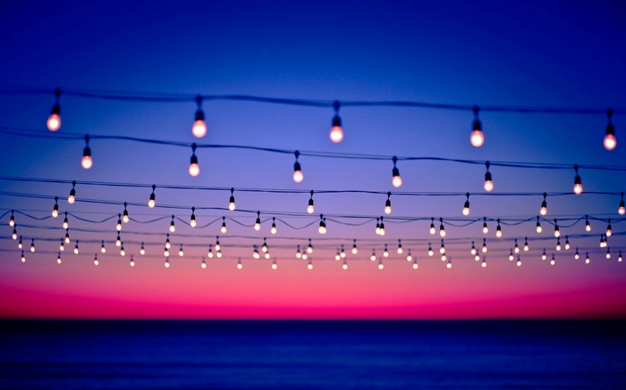 String lights over the ocean at sunset