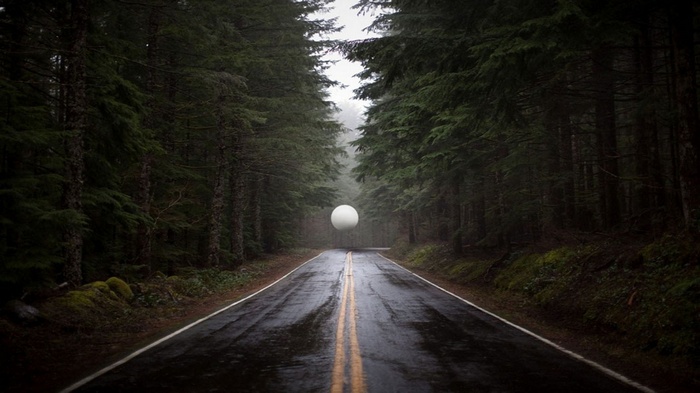 White sphere floating over a wet forest road