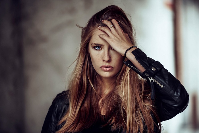 Woman with blue eyes and freckles wearing a leather jacket