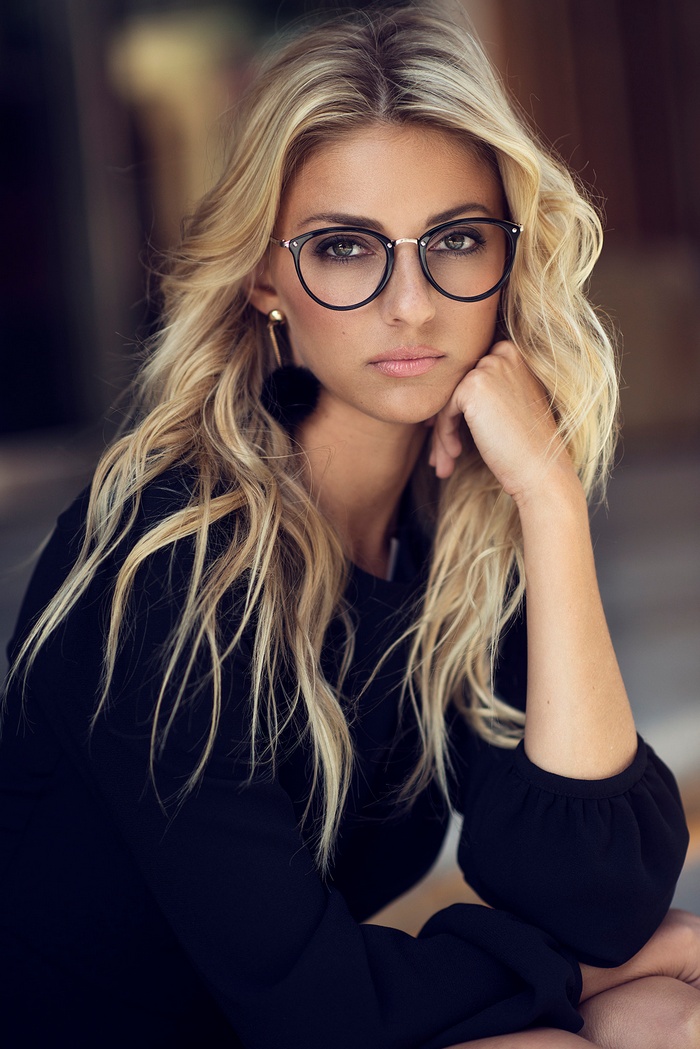 Woman with blonde hair wearing glasses and black top