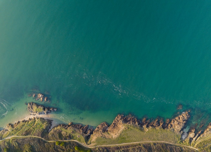 Aerial view of a rocky coastline meeting turquoise water