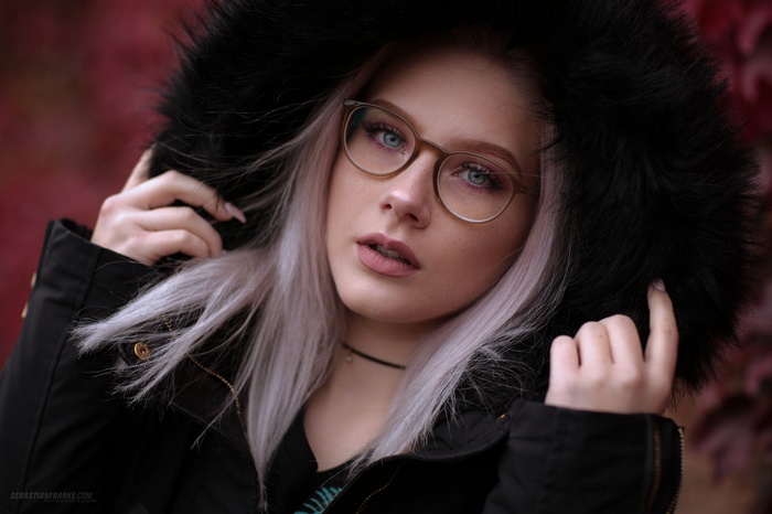 Woman with blonde hair and glasses wearing a black jacket