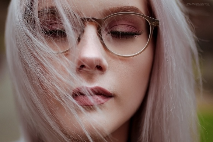 Close-up portrait of a woman with glasses and pink eyeshadow