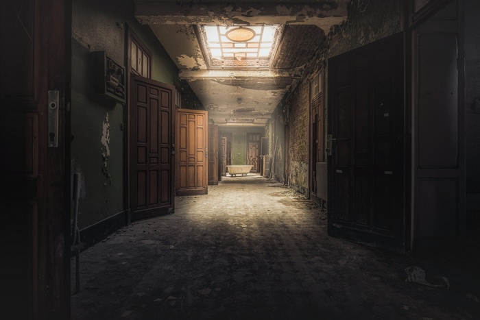 Abandoned hallway with bathtub and open doors