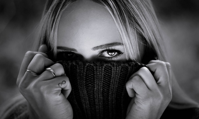 Woman hiding face with sweater, looking at viewer
