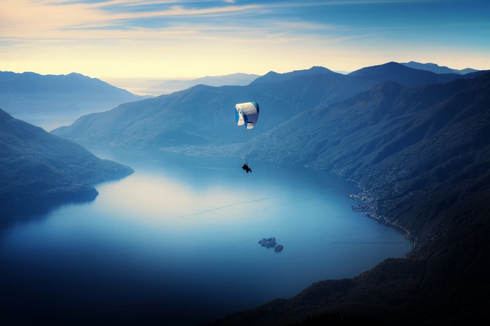 Paraglider over a mountain lake at sunset
