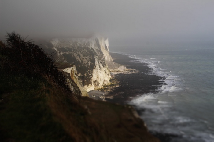 White cliffs of Dover in mist with waves crashing on shore
