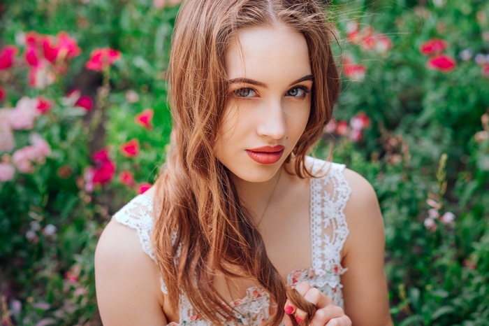 Woman with long brown hair and red lipstick outdoors