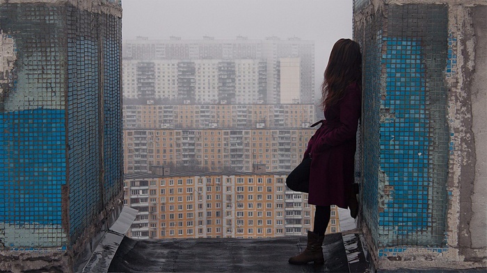 Woman in red coat on rooftop overlooking Moscow cityscape