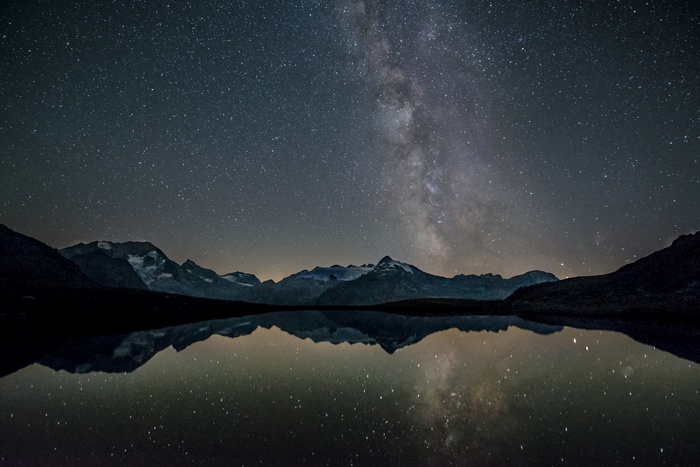 Milky Way over snow-capped mountains reflected in a lake