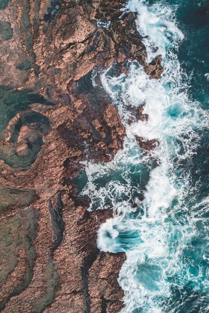 Aerial view of ocean waves crashing on rocky shore