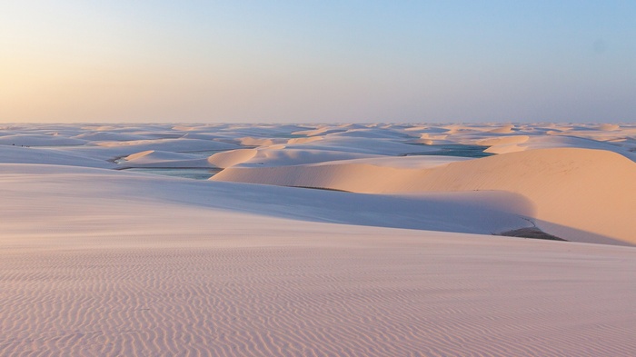 Desert sand dunes with pools of water at sunset