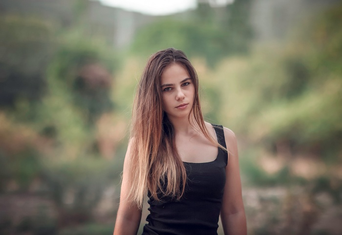 Young woman with long blonde hair in a black tank top outdoors