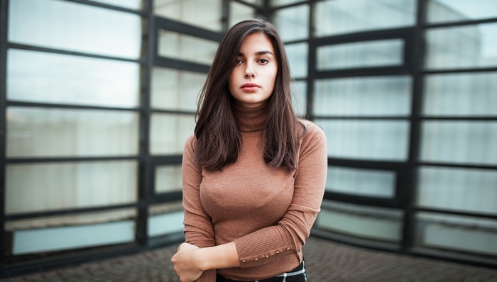 Woman in a turtleneck standing in front of windows