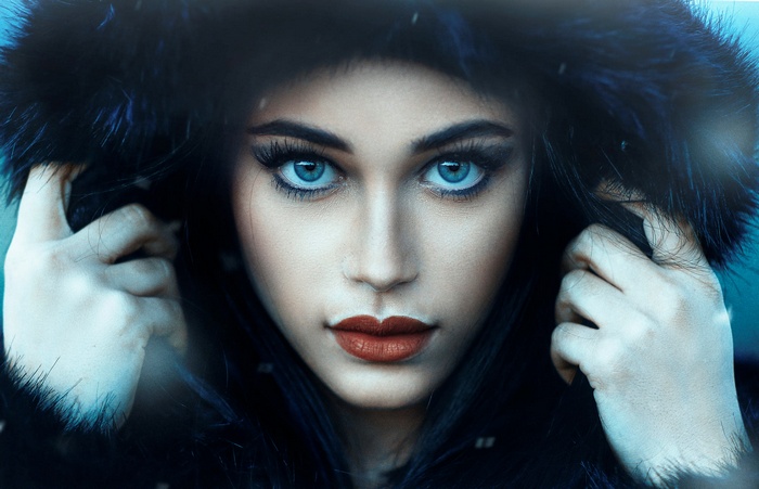 Woman with blue eyes and red lipstick wearing a fur hood
