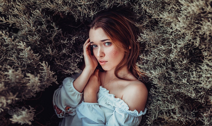 Woman with freckles lying in foliage