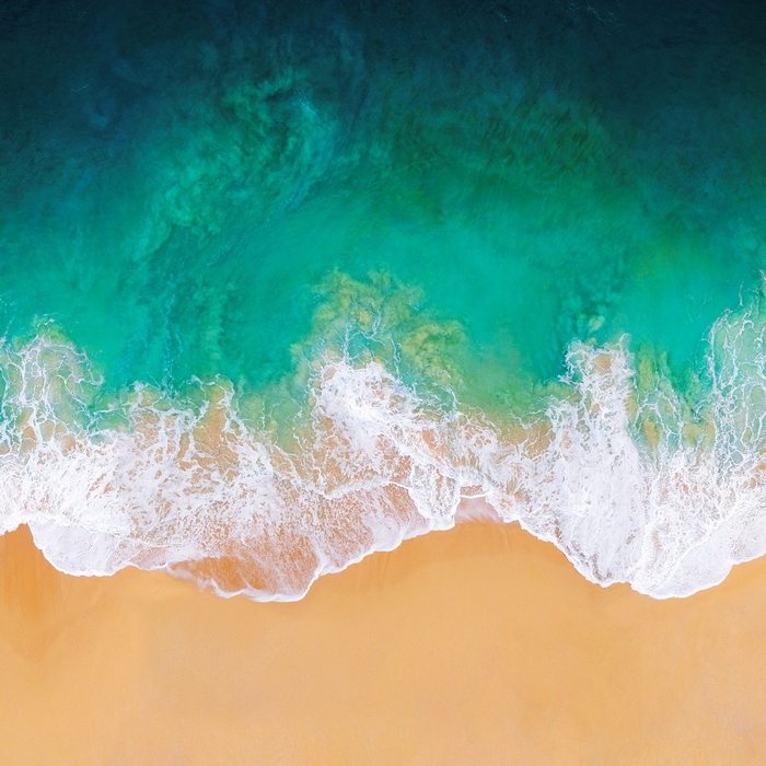 Aerial view of ocean waves crashing on a sandy beach