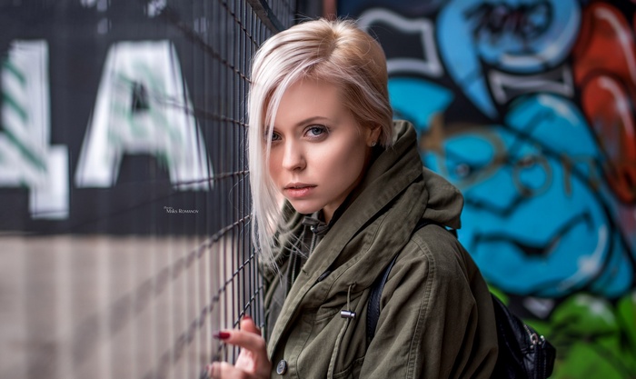 Woman with blonde hair in a green jacket near graffiti