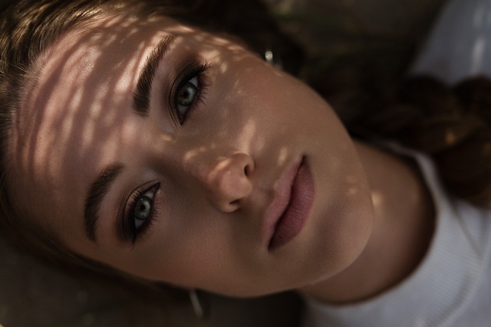 Close-up portrait of a young woman with dappled light on her face