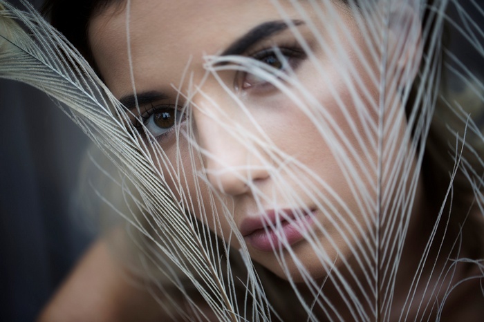 Woman with brown eyes behind feathers