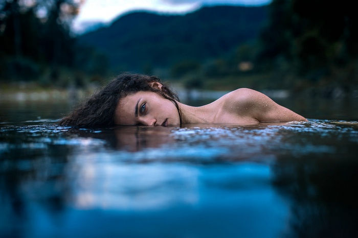 Woman with curly hair lying in water