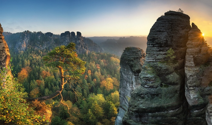 Rocky mountain landscape with autumn forest and sunrise