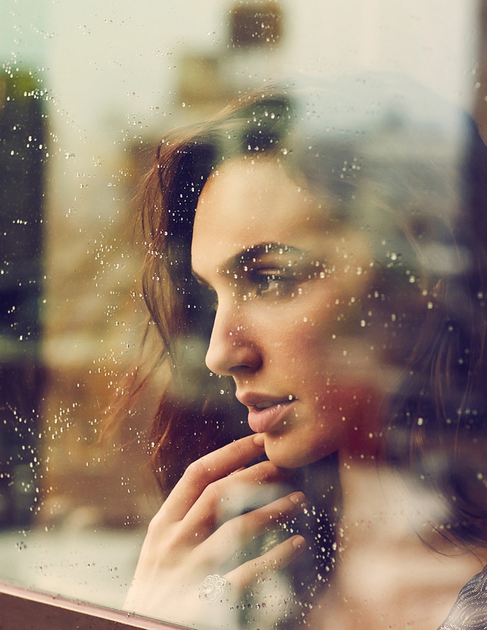 Gal Gadot looking through a rainy window