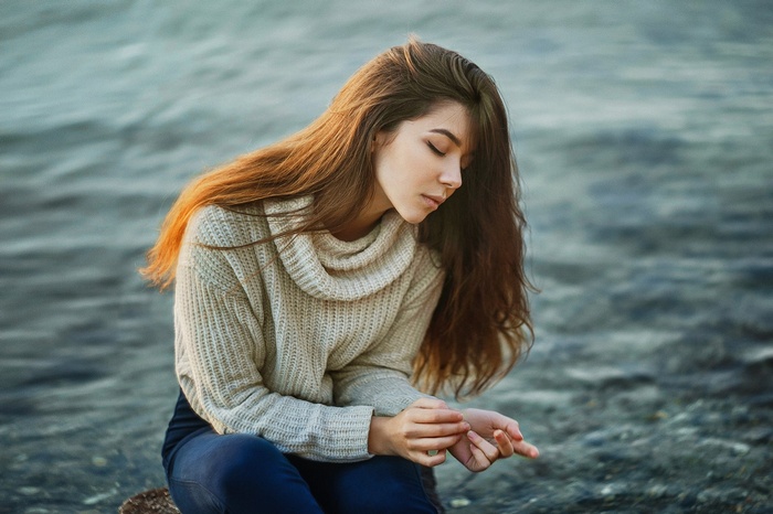 Woman with long hair sitting by the water