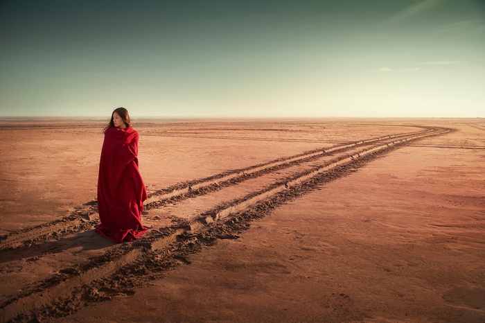 Woman in red blanket in desert landscape