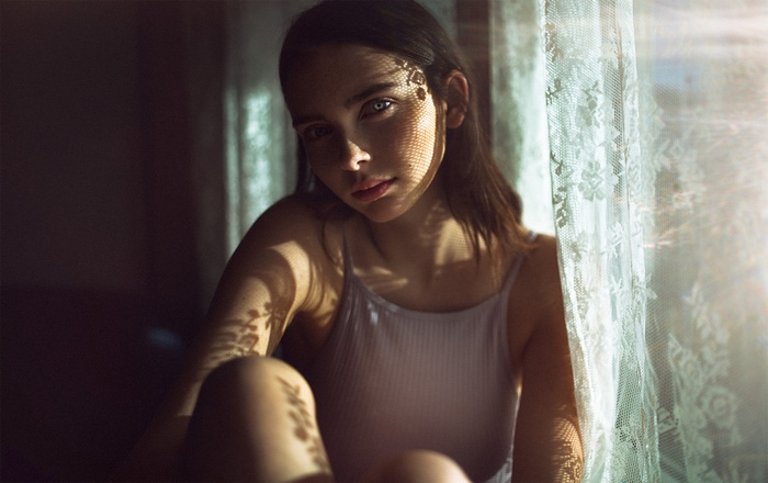 Woman sitting by a window with lace curtains